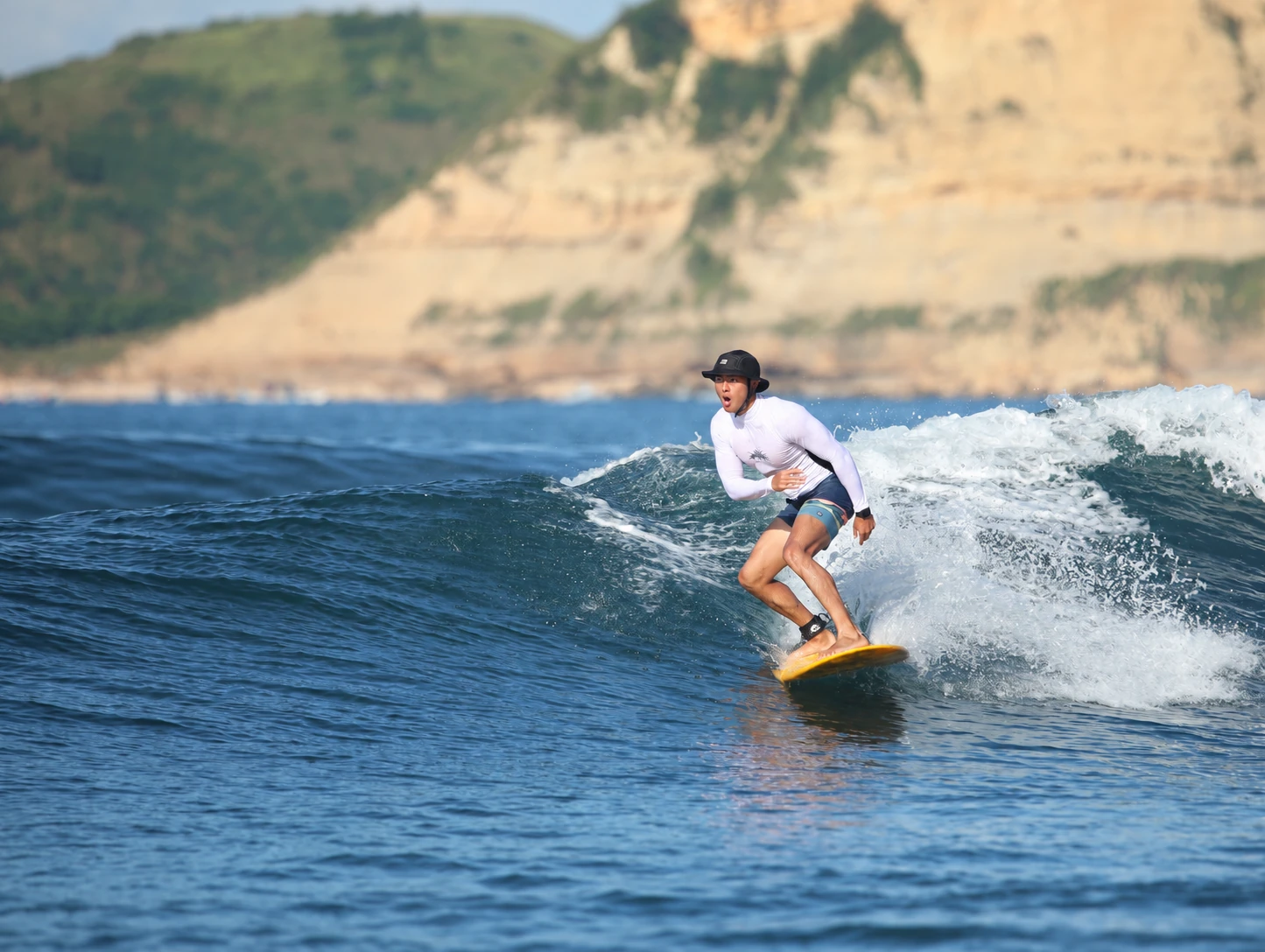 Zeyu Tyger Wen surfing along a natural coastline